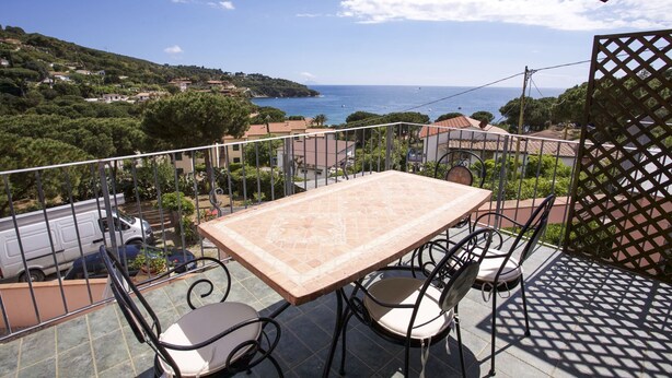 A balcony with a table and chairs overlooking a coastal view. - APP.TI MORCONE - MORCONE BILO 1 (Capoliveri)