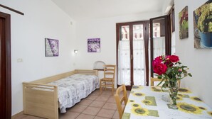 A small room with a single bed, a table with a sunflower tablecloth, and a vase with flowers. - APP.TI MORCONE - MORCONE BILO 4 (Capoliveri)