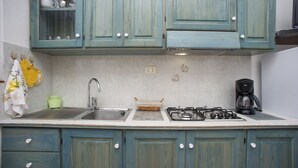 A kitchen with teal cabinets, a sink, a stove, and a coffee maker. - APP.TI MORCONE - MORCONE BILO 4 (Capoliveri)