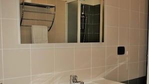 Ein Badezimmer mit einem weißen Waschbecken, einem Spiegel und einer Duschkabine.
