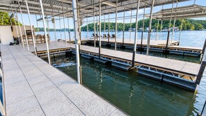 A covered dock area with multiple levels of seating and a view of a lake.