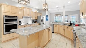 A modern kitchen with granite countertops, stainless steel appliances, and wooden cabinets. - A 5500 sq ft.Luxury Home~Huge Boat Dock~Perfect for Large Groups~Waterfront~Pool Table~Firepit (Camdenton)