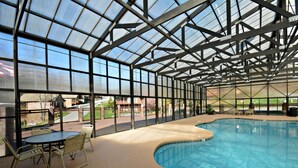 An indoor swimming pool with a glass ceiling, surrounded by a poolside area with chairs and a table. - Mountain View from front Porch and private Hot tub on the back porch! (Sevierville)