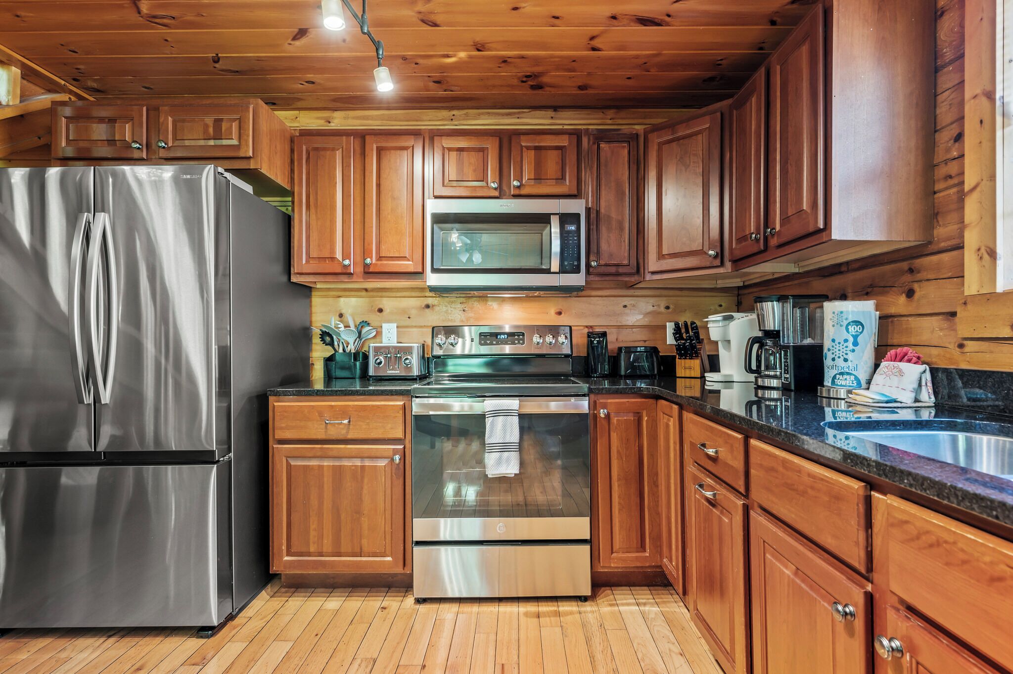A modern kitchen with wooden cabinets, stainless steel appliances, and a granite countertop.