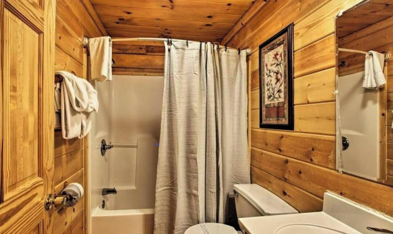 Ein Badezimmer einer Holzhütte mit Badewanne, Toilette und Waschbecken.