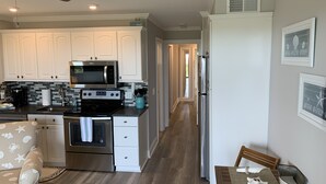 A modern kitchen with white cabinets, a microwave, stove, and a dining area with a table and chairs.