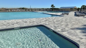 A large outdoor swimming pool with multiple lanes, surrounded by lounge chairs and a tiled deck.