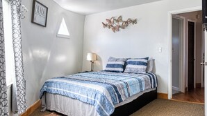 Een slaapkamer met een bed, een bedlamp, een raam en een decoratie aan de muur.