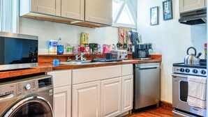 Een praktische keuken met een wasmachine, vaatwasser, kookplaat en diverse keukengerei.