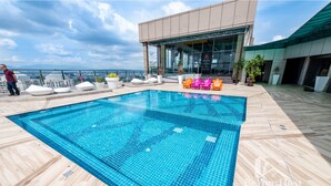 A rooftop pool with a clear view of the city skyline, surrounded by modern lounge chairs and potted plants. - Dorsett Residences by BeYourHost (Kuala Lumpur)