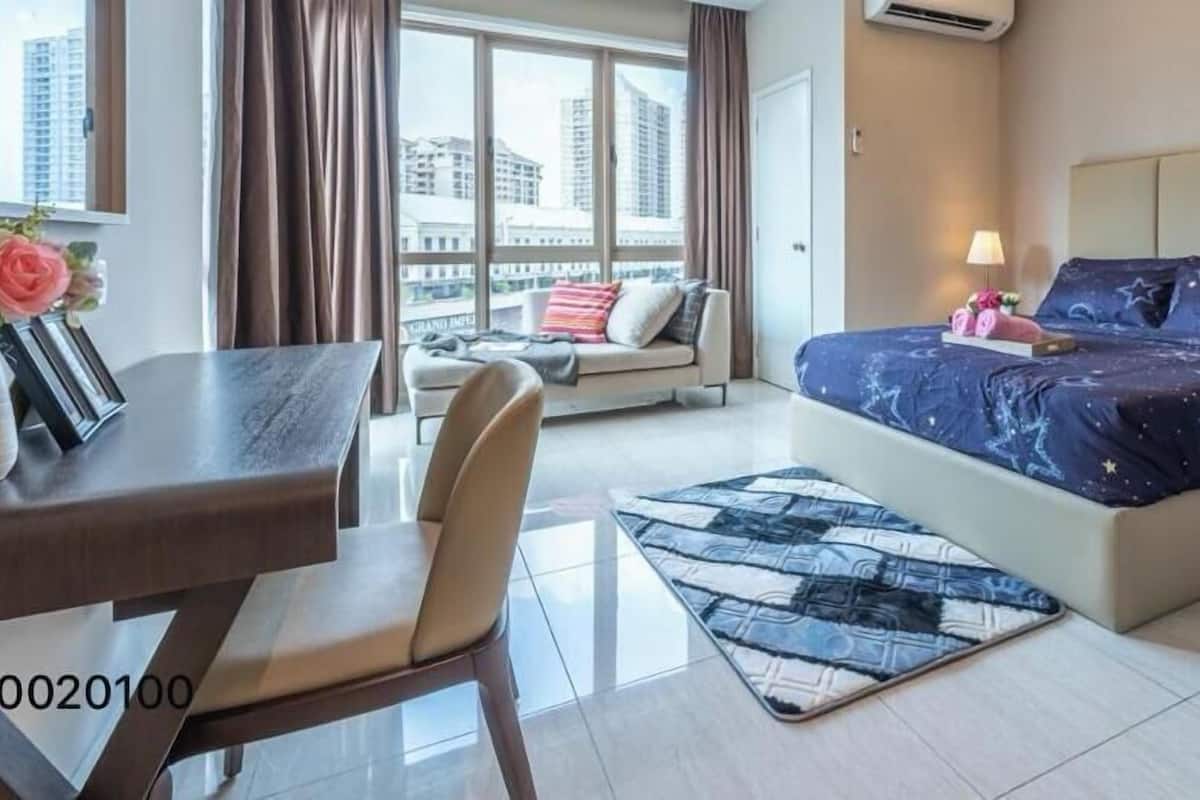 Ein modernes Hotelzimmer mit Bett, Sofa, Esstisch und Blick auf die Stadtlandschaft.