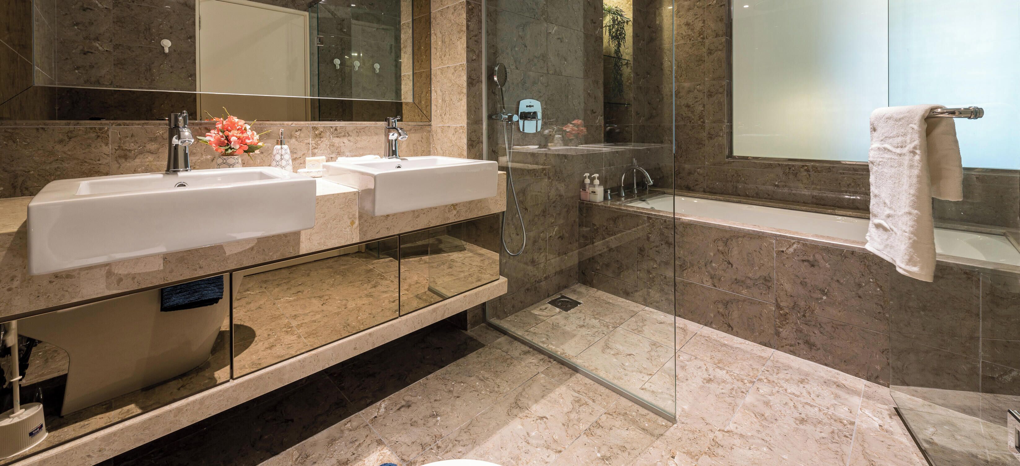 A modern bathroom with two sinks, a glass-enclosed shower, and a large mirror.