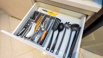 Un cajón con utensilios de cocina y un par de tijeras amarillas.