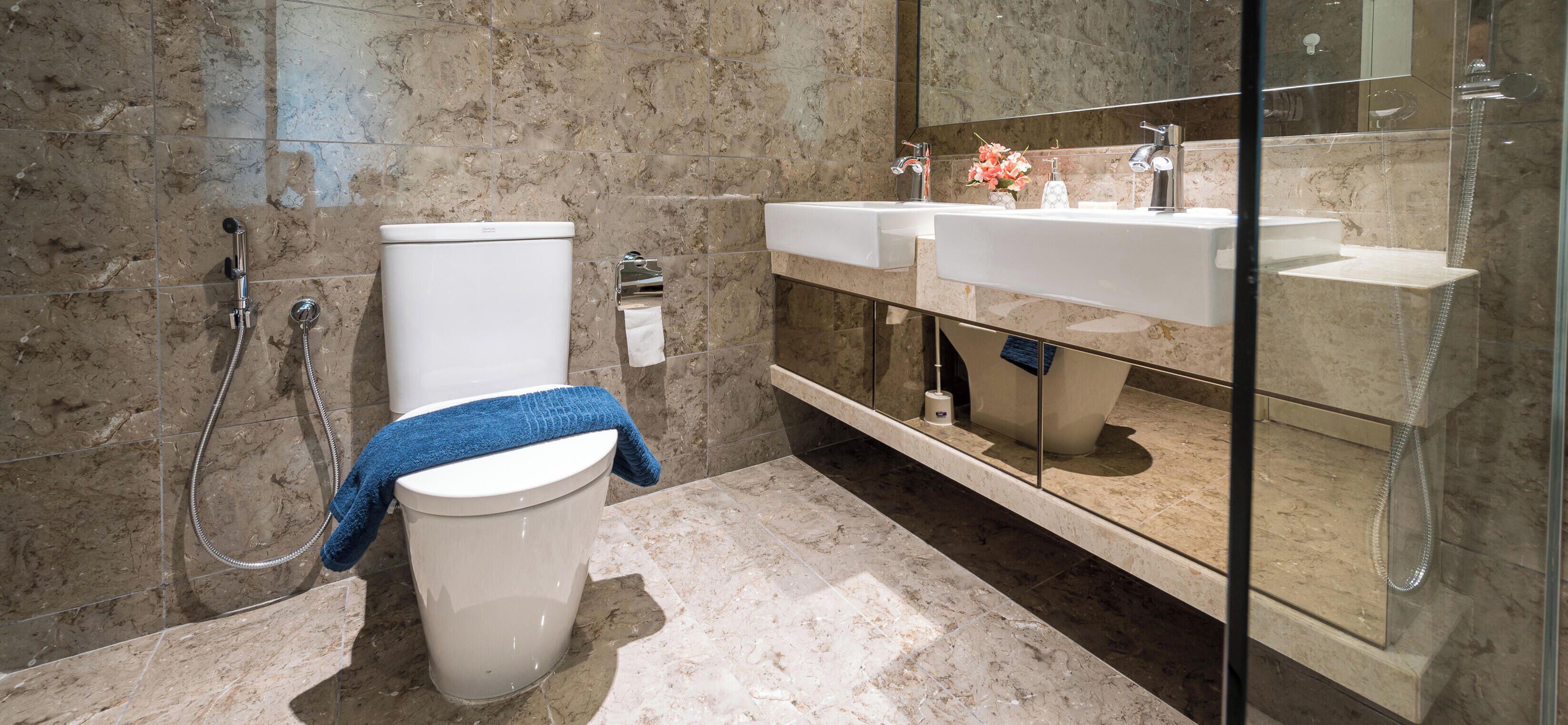 Ein Badezimmer mit Toilette, Bidet und einem Waschbecken mit Spiegel und Glasabtrennung.