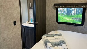 A compact room with a bed, a small window with a forest view, a sink, and cabinets. - Fully sanitized with bbq & lawn, super soft linens, safe, country setting (Arroyo Grande)