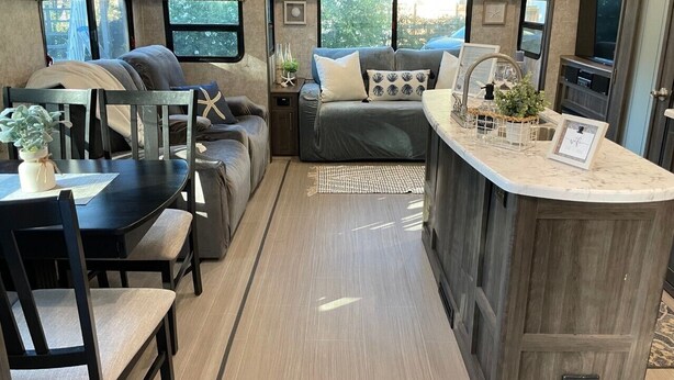 A compact RV interior with a kitchenette, a dining area, and a seating area with a sofa and chairs. - Fully sanitized with bbq & lawn, super soft linens, safe, country setting (Arroyo Grande)
