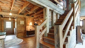 A rustic wooden interior with a staircase, wooden walls, and a dining area.