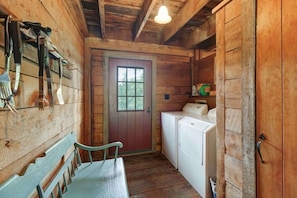 Cozy cabin-style room with a bench, door with a window, and washing machine.