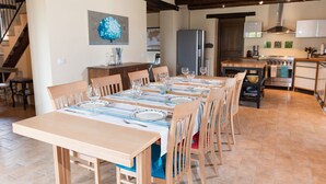 A dining area with a long table set for six, wooden chairs, and a kitchen in the background. - Casa Pace e Gioia - Restored farmhouse with private pool and amazing views (Tolentino)