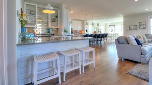 A spacious kitchen with a central island, bar stools, and pendant lighting. - ☀️Spice Island-7BR Oceanfront-Saltwater Pool-Private Beach Access☀️ (Carolina Beach)