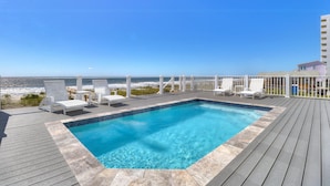 A rectangular pool with a wooden deck and white lounge chairs, overlooking a beach and ocean. - ☀️Spice Island-7BR Oceanfront-Saltwater Pool-Private Beach Access☀️ (Carolina Beach)