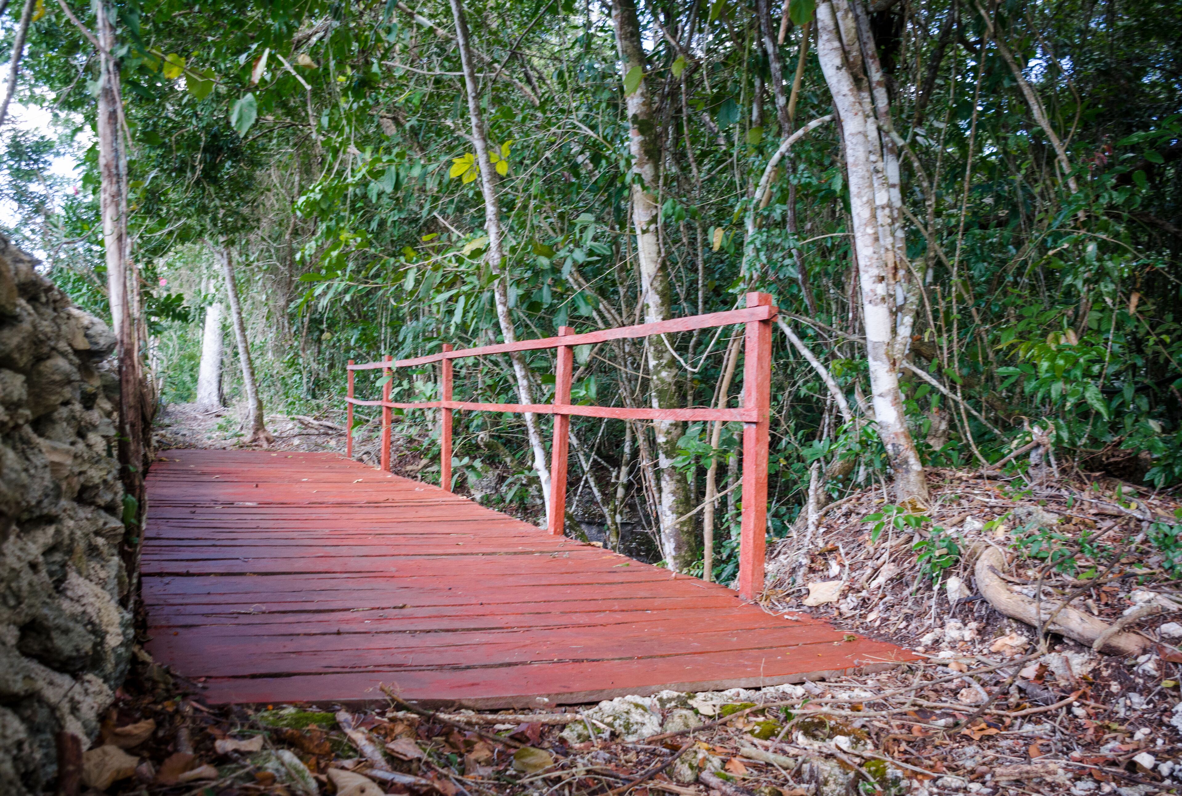A red wooden bridge in a forested area.