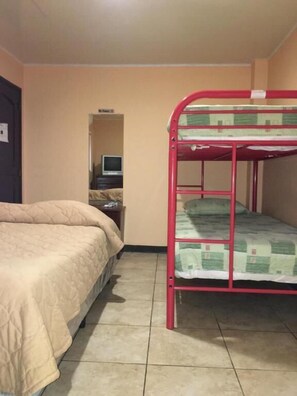 Un dormitorio con literas, un escritorio con computadora y una cama con colcha.