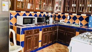 A kitchen with wooden cabinets, a microwave, a toaster, and a gas stove. - Ecotel (Managua)