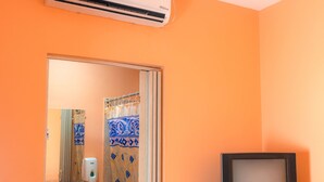 A bathroom with an air conditioner, a sink, a mirror, and a television. - Ecotel (Managua)