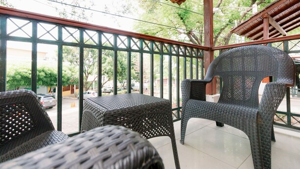A covered outdoor seating area with wicker furniture and a view of the street. - Ecotel (Managua)