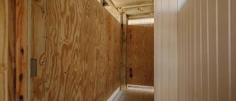 Un couloir étroit aux murs en bois, avec une porte blanche au fond.
