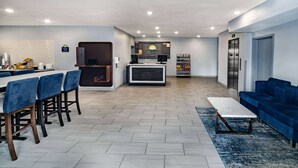 A modern hotel lobby with a dining area, a kitchen, and a living room.