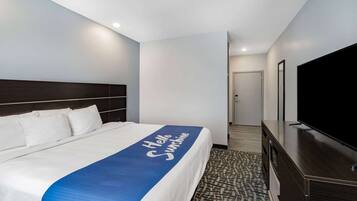 Una habitación de hotel con una cama, televisión y un pasillo que lleva a una puerta.