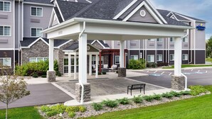 A hotel with a covered entrance, stone pillars, and a parking lot.