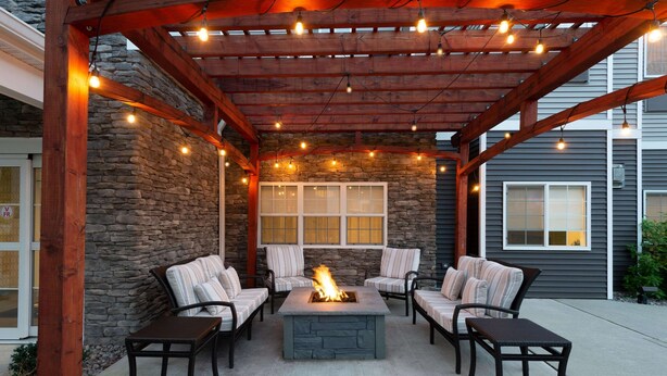 An outdoor patio with stone walls, a fire pit, and four chairs.