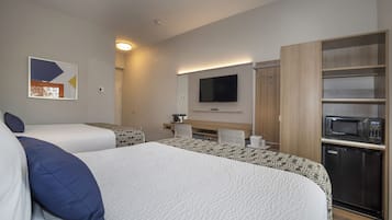 Hotellihuone, jossa on kaksi sänkyä, televisio, mikroaaltouuni ja pieni keittonurkkaus.
