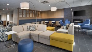 Eine moderne Hotelhalle mit Sitzbereichen, einem Flachbildfernseher und einem Kamin.