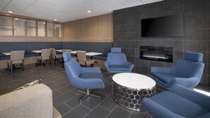 Ein moderner Lounge-Bereich mit blauen Sitzgelegenheiten, einem Flachbildfernseher und einem Kamin.