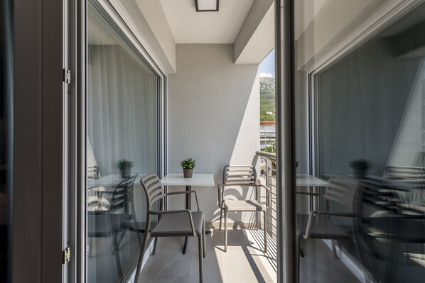 A balcony with a table and chairs, a potted plant, and a view of the cityscape. - Ringo Apartments (Podstrana)