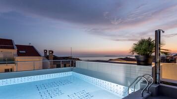 A rooftop pool with a clear view of the city skyline at sunset.