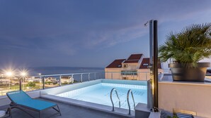 Uma piscina no terraço com uma espreguiçadeira azul e um vaso de planta.