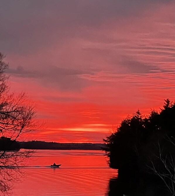 Ein Sonnenuntergang über einem ruhigen See mit der Silhouette eines Bootes.