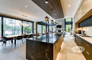 A modern kitchen with a large island, dark cabinetry, and a stone backsplash.