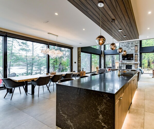 Una cocina moderna con una isla grande, muebles oscuros y un salpicadero de piedra.