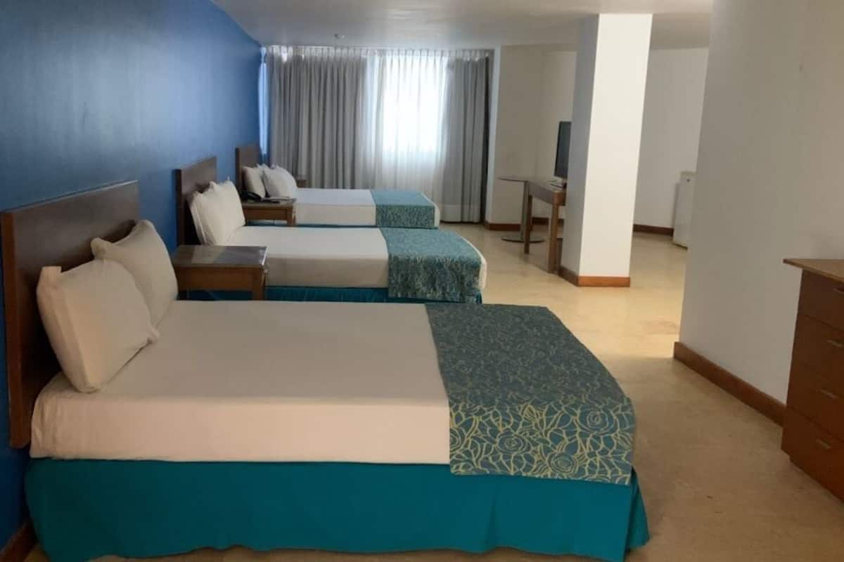 Et hotelværelse med to senge, et skrivebord og et fjernsyn.