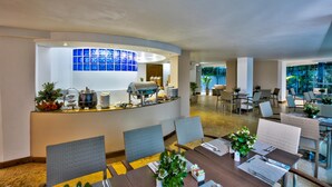 Un moderno vestíbulo de hotel con una zona de recepción, mesas y sillas para comer.