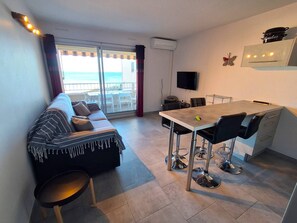 A modern living room with a sofa, a dining table, and a TV.