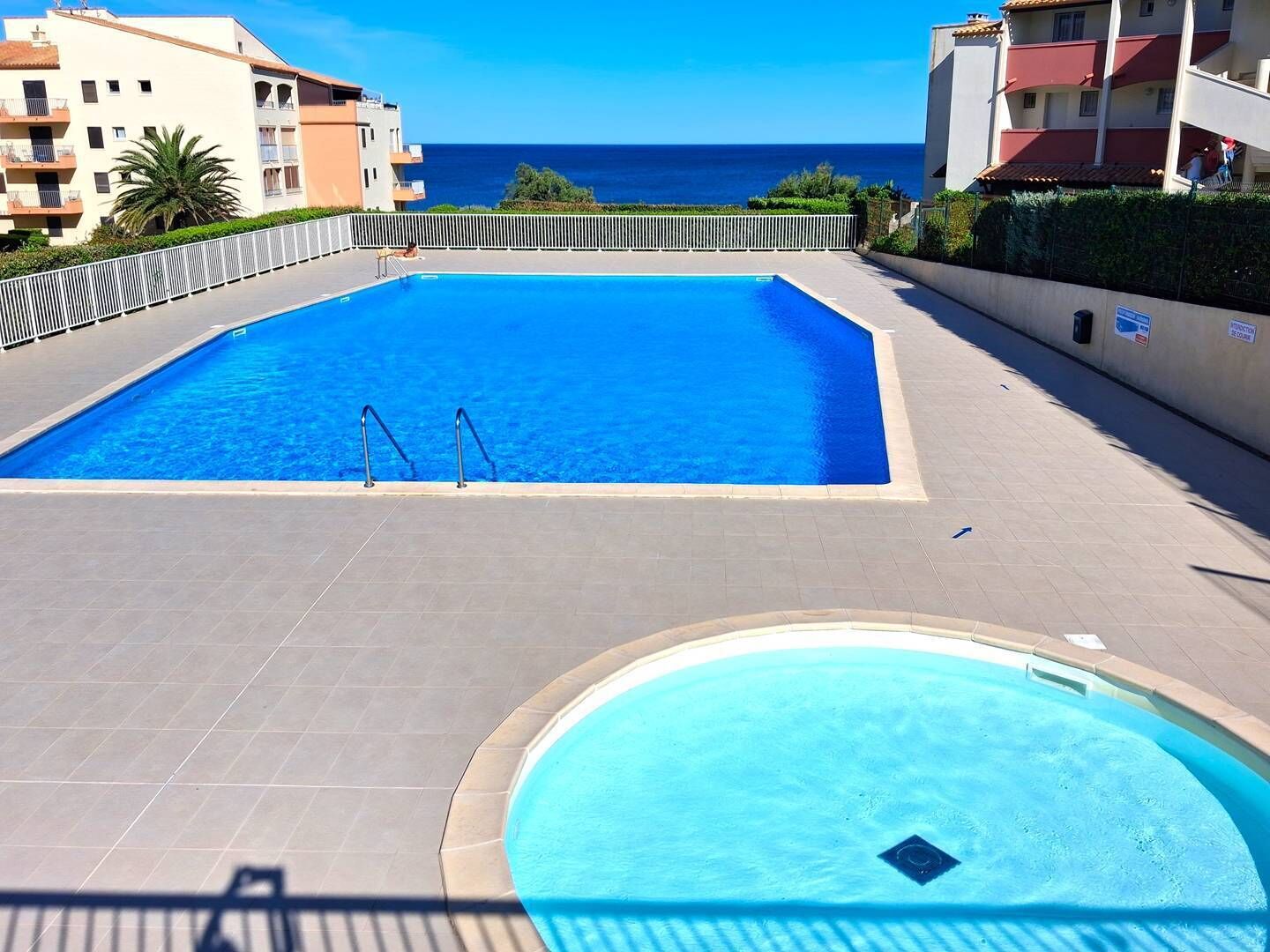 Ein Pool mit Blick auf das Meer, umgeben von Gebäuden.