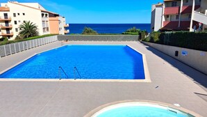 En swimmingpool med utsikt över havet, omgiven av byggnader.
