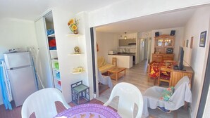 Ett kompakt bostadsutrymme med en matplats, ett kök och en liten sittgrupp.